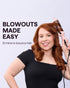 Woman with styled hair using a hair dryer on a light purple background with text 'Blowouts Made Easy'.